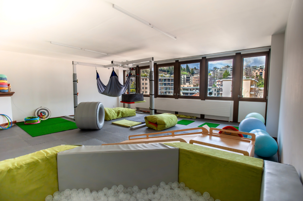 Sala luminosa con attrezzature e giochi per la riabilitazione pediatrica.