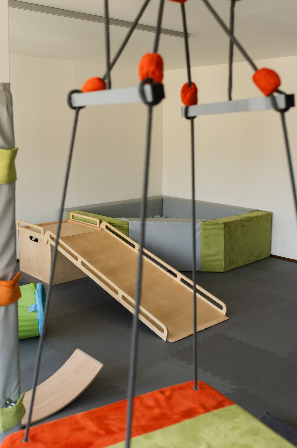Area giochi motoria indoor per bambini presso Polispecialistico Paradiso Lugano, con scivolo sensoriale e piscina di palline.