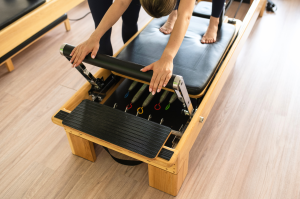 Dettaglio di un macchinario Pilates Reformer regolato da un’istruttrice.