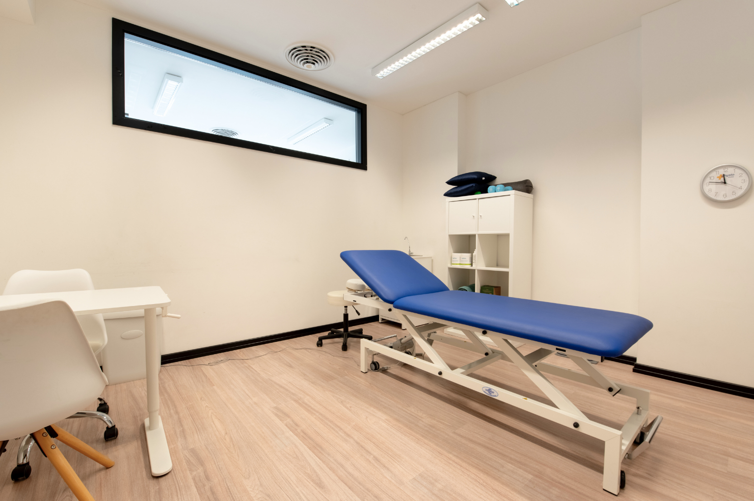 Studio di fisioterapia del Polispecialistico Paradiso con lettino blu, scrivania e arredi bianchi.